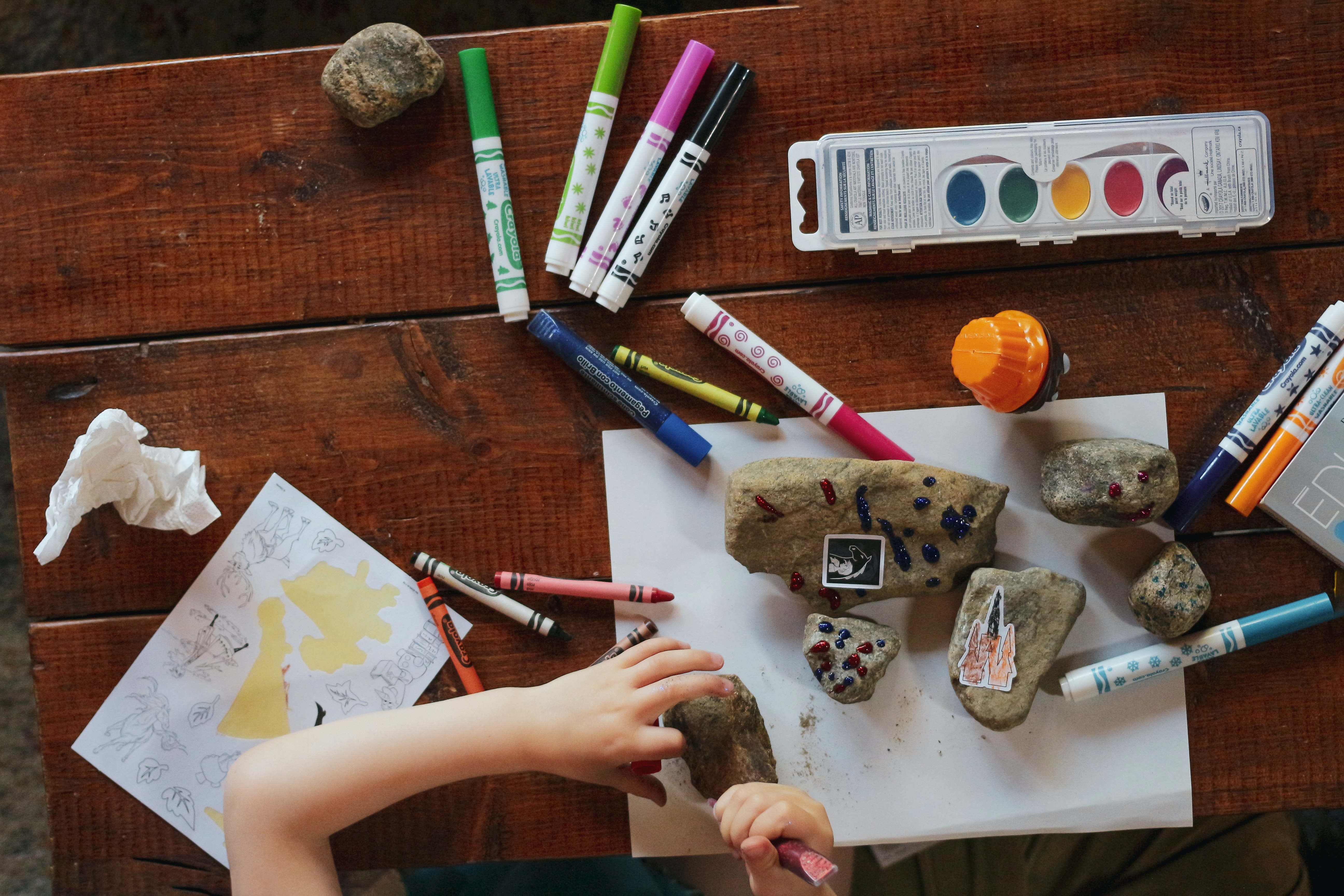 Overhead view of child painting on rocks at table