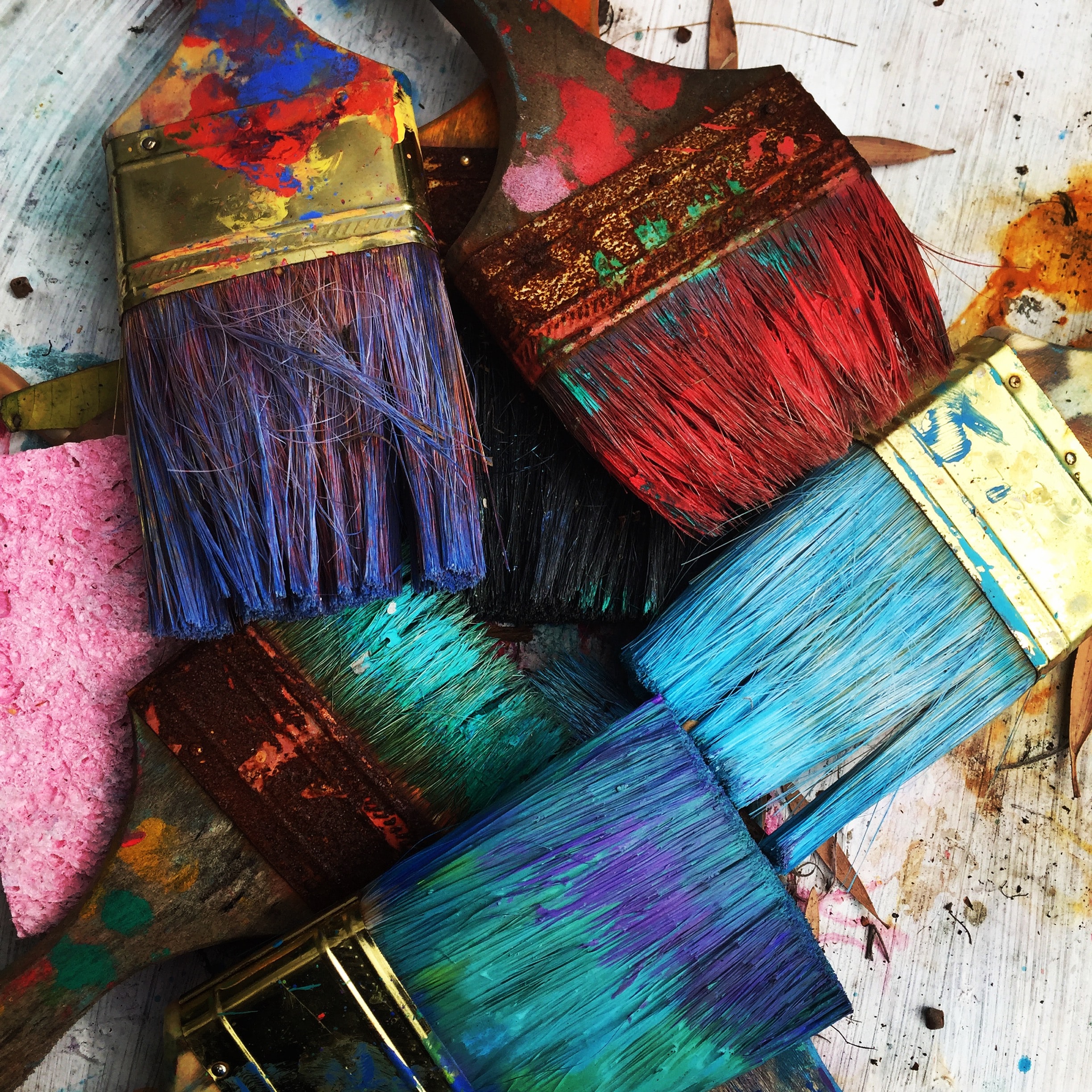 Group of paintbrushes with bristles stained shades of red, purple, blue, and green