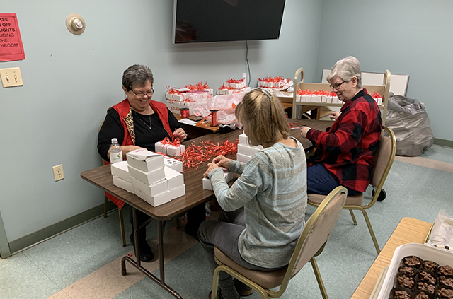 Volunteers seated at table wrapping boxes for library fundraiser