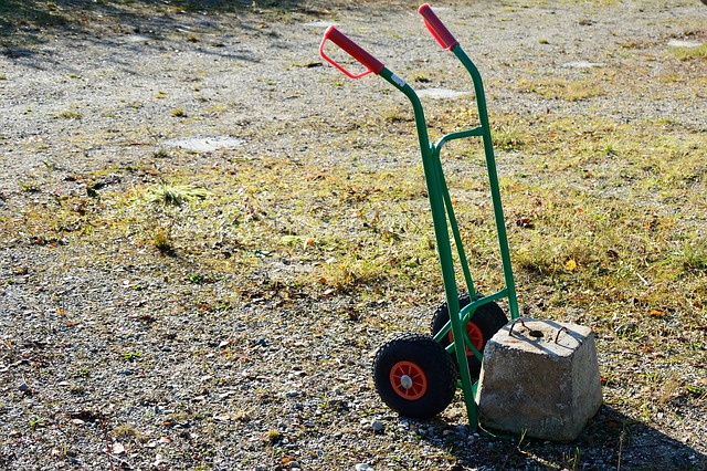 Green hand truck moving a concrete block