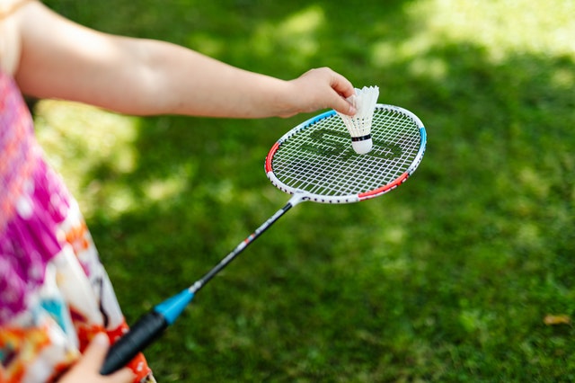 Hand placing badminton shuttlecock on racket