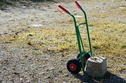 Green hand truck moving a concrete block